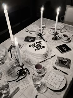 a white cake sitting on top of a table covered in plates and glasses with lit candles