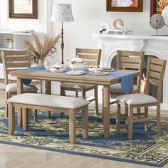 a dining room table with chairs and a blue rug in front of the fire place