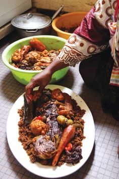 a woman is cutting up food on a plate in front of two bowls filled with meat and vegetables