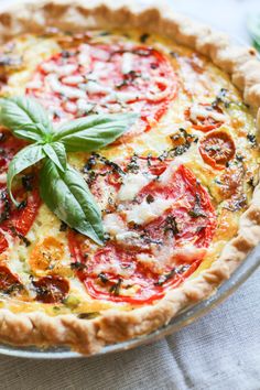 a fresh tomato and basil quiche on a glass plate with a leafy green garnish