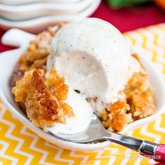 a scoop of ice cream sits in a bowl on a yellow and white tablecloth