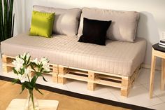 a couch made out of wooden pallets in a living room next to a table