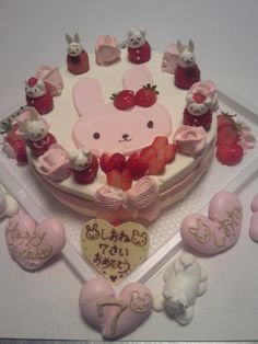 a cake decorated with pink and white icing, strawberries, and bunny ears