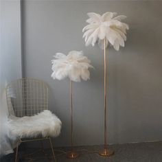 two tall white feather lamps next to a chair