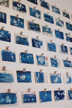 several pieces of blue and white art hanging on a wall with metal clips attached to it