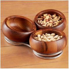 three wooden bowls filled with nuts on top of a table