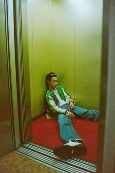 a man sitting on the floor in an elevator with his feet up and head down