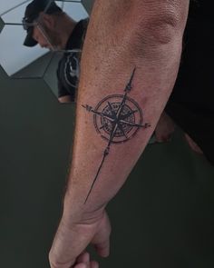 a man's arm with a compass tattoo on it