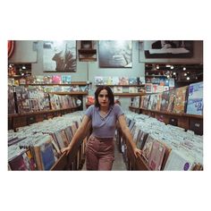 a woman is standing in the aisle of a record store