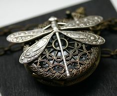 Perched on an ornate filigree pocket watch is an antiqued silver dragonfly. The watch really works :) Adjust time by popping up the button (pull it straight up), and open the watch by pressing the button down. Battery can be changed by a jeweler if needed. I inspect watches to ensure battery is operating before shipping out. The watch is 38mm in diameter and flies from a 24 inch large linked heavy-duty chain. I can make length modifications upon request. CUSTOMER FEEDBACK FOR THIS DESIGN: Love t Silver Antique Finish Pocket Watch Gift, Steampunk Silver Pocket Watch With Locket, Silver Steampunk Pocket Watch With Locket, Dragonfly Photos, Pocket Watch Necklace, Love T, Chain Extenders, Watch Necklace, Made Goods