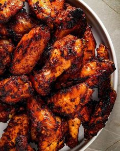 a white bowl filled with chicken wings on top of a table