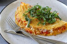 an omelet on a plate with fork and knife