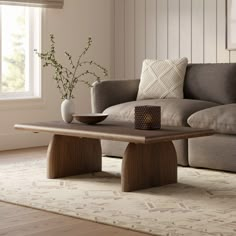 a living room with a couch, coffee table and vase on the floor in front of it