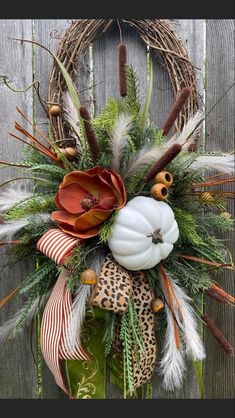 a wreath decorated with feathers, flowers and other decorations on a wooden fence door hanger