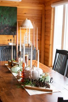 a wooden table topped with lots of candles and pumpkins on top of each other