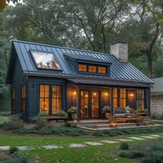 a small blue house with lots of windows and lights on the front door is surrounded by greenery