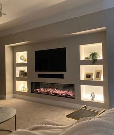 a living room with a large television mounted on the wall and built - in shelving