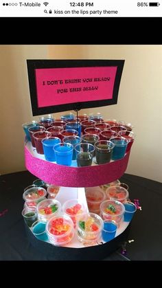 a table topped with cups filled with different colored drinks and candies on top of each other