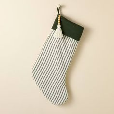 a green and white striped stocking hanging on a wall with a wooden bead