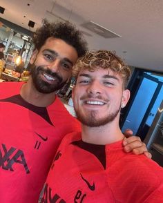 two men in red shirts posing for the camera