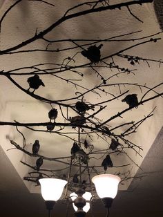 a chandelier hanging from the ceiling with birds perched on branches in front of it