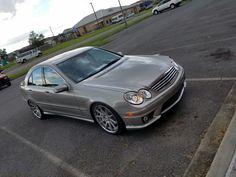 a silver car parked in a parking lot next to other cars on the side of the road