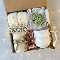 an open box containing two mugs and flowers