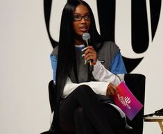 a woman sitting in a chair holding a microphone