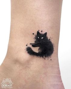 a black cat tattoo on the ankle with watercolor paint splatters all over it