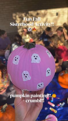 a person holding up a pumpkin with ghost faces on it and the words, fun fall sisterhood activity pumpkin painting crumbs