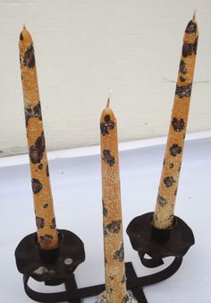 three candles sitting on top of each other in front of a white wall and black stand