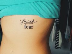 a woman's stomach with the words faith and fear tattooed on her lower back