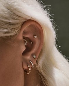 a woman with blonde hair is wearing three different ear piercings on her left side