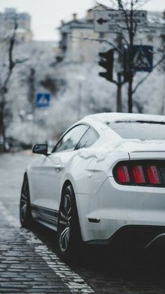 the rear end of a white mustang parked in front of a traffic light on a city street