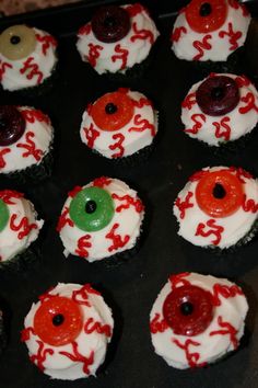 cupcakes decorated with white frosting and red icing are arranged in the shape of eyeballs