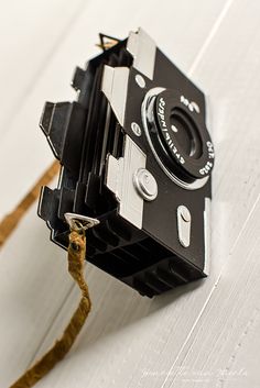 an old fashioned camera sitting on top of a white table next to a brown rope