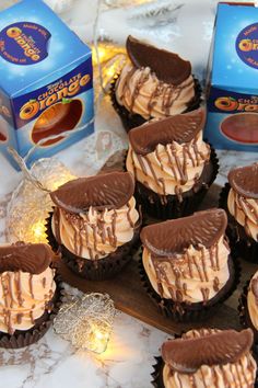 chocolate cupcakes with peanut butter frosting on a table next to boxes of milk