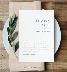 a white plate topped with a napkin next to a green leafy plant on top of a wooden table