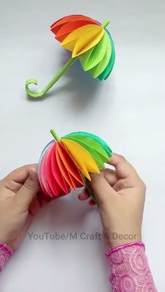 two hands are holding colorful paper umbrellas