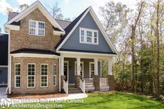 a brick house with white trim on the front porch and two story windows, surrounded by green grass