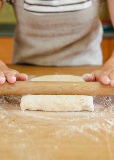 a person rolling dough on top of a wooden table