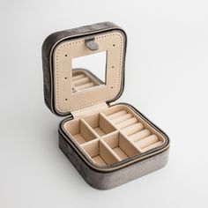 an open case with compartments for jewelry on a white surface, showing the inside compartment