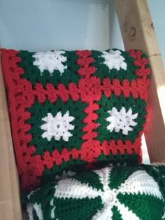 a crocheted blanket and pillow sitting on top of a wooden chair