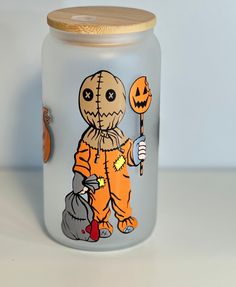 a glass jar with an image of a scarecrow holding a jack - o'- lantern