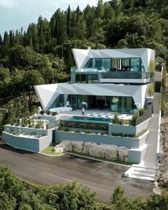 an aerial view of a modern house in the mountains with pool and stairs leading up to it