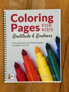 coloring pages for kids with crayons and markers on the cover, sitting on a wooden surface