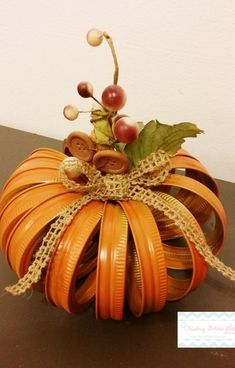 an orange decorative pumpkin with leaves and berries on it's top, sitting on a table