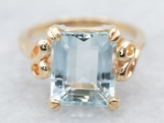 "The clean lines of this perfectly faceted aquamarine gemstone are a perfect match for the looping shoulders of the yellow-gold, vintage mounting we have set it in! This is an elegant piece, filled with color and shine! Metal: 14K Yellow Gold Gem: Aquamarine 2.75 Carats Gem Measurements: 9.7 x 8.0 mm, Emerald Cut Ring Size: 4.50 Marks: \"14K\" Stamped on the inside band To view a video of this piece check out the link below: https://vimeo.com/793383685 SKU #:  A19273 Each piece has been identifi Gold Aquamarine Ring, Aquamarine Solitaire Ring, Ring Blue Stone, March Birthstone Ring, Petite Earrings, Ring Emerald Cut, Emerald Cut Rings, Blue Stone Ring, Ring Emerald