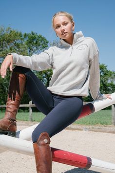 a young woman sitting on top of a white and red fence next to a horse