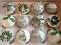 twelve christmas baubles in a box decorated with white and green decorations, including holly wreaths